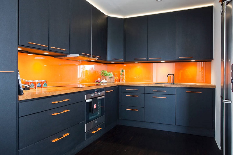 Темно-синие или же черные кухонные фасады отлично оттенят интенсивный оранжевый