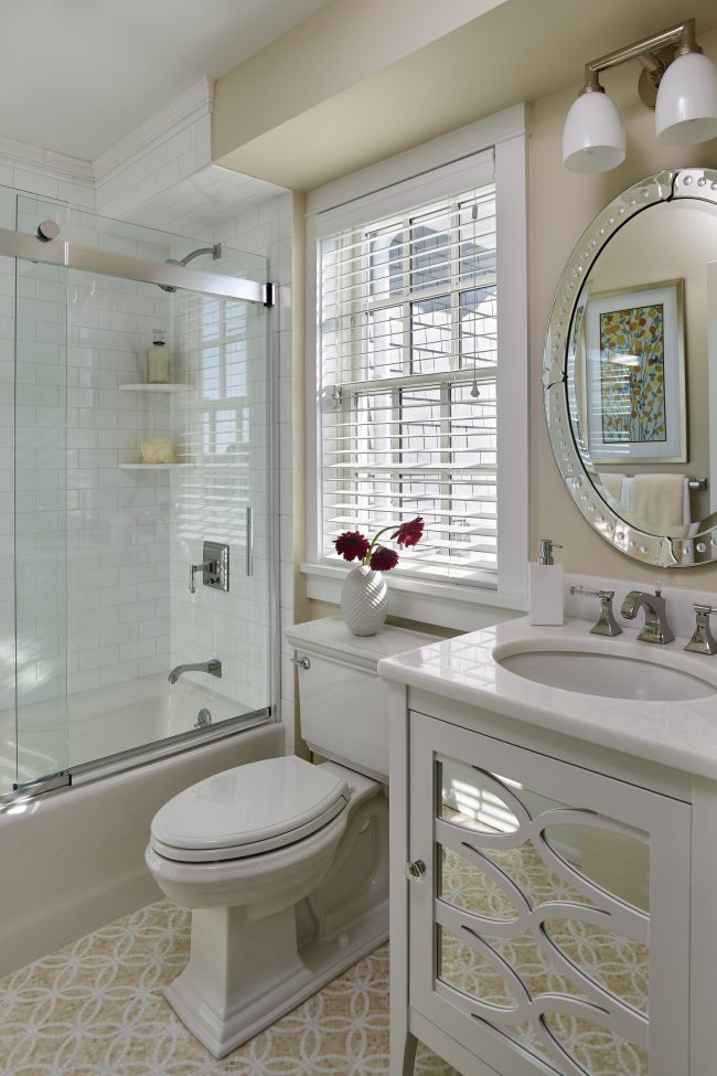 Надежно закрепленная металлическими пластинами стеклянная раздвижная шторка в светлой ванной