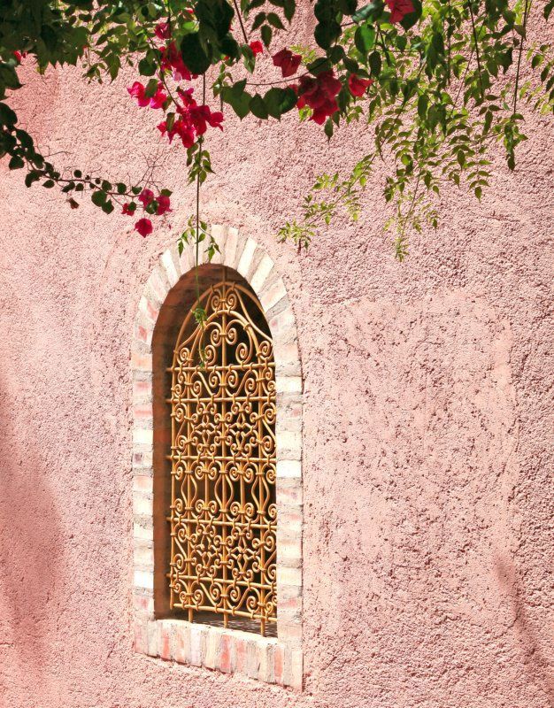 Ажурная решетка желтого цвета - оригинальное украшение на фоне розового фасада дома 