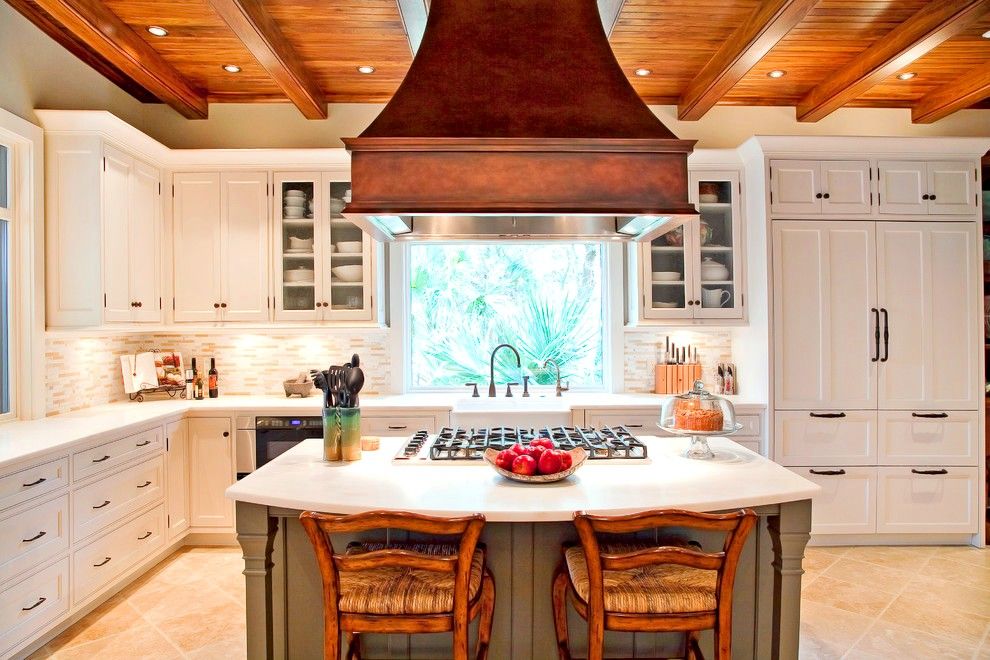Большая деревянная вытяжка на встроенной кухне станет ярким элементом на фоне белой мебели