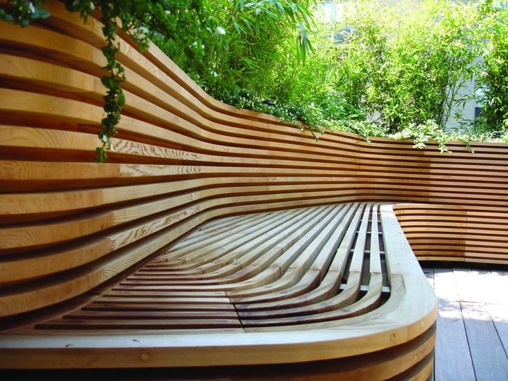 Деревянная скамейка из множества элементов гармонично смотрится в саду