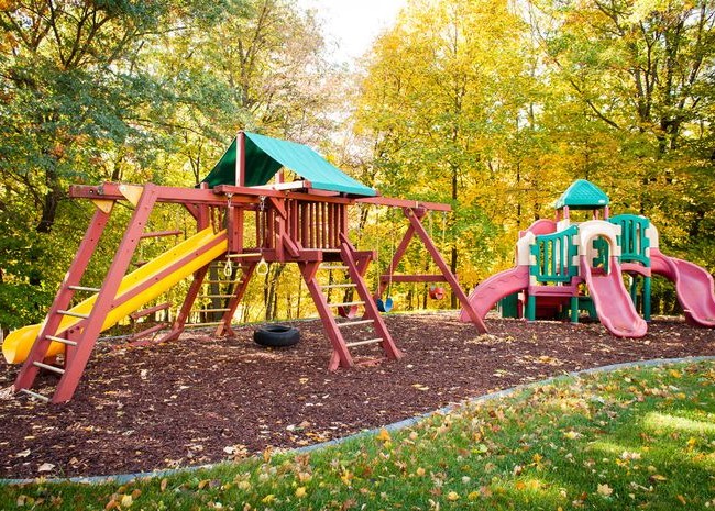 Яркая детская площадка очень красиво смотрится на фоне осенней листвы