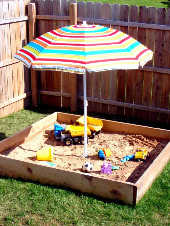 Простая квадратная песочница из нескольких досок с солнцезащитным зонтом