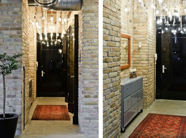 Узкая прихожая стандартной квартиры со светлыми кирпичными стенами и эффектным верхним освещением