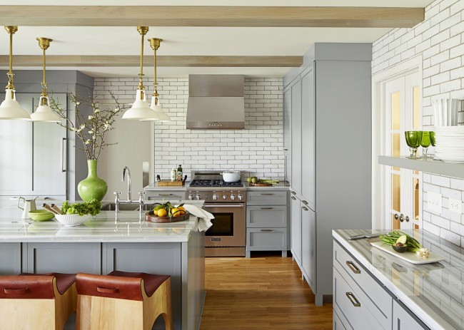 Просторная кухня-студия с белой кирпичной кладкой на стенах и яркими зелеными акцентами в интерьере