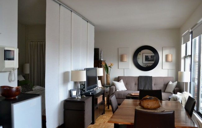 Сдвижные белые шторы отделяют спальное место от зоны гостиной