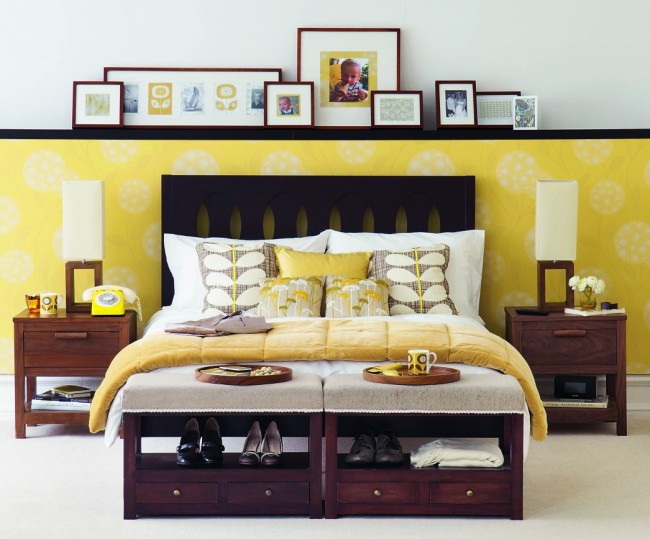Уютная спальня с желтыми акцентами и оригинальным решением комбинирования: панель разделяющая разноплановые обои также выполняет функцию небольшой полочки для фотографий