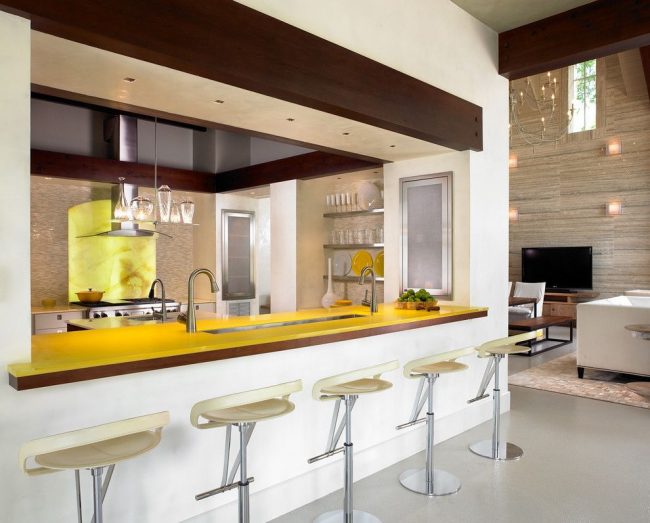 Яркая желтая столешница барной стойки выполнена из пластика. Пластик – современный материал, беспроигрышно подходящий для кухонь в стиле хай-тек и минимализм