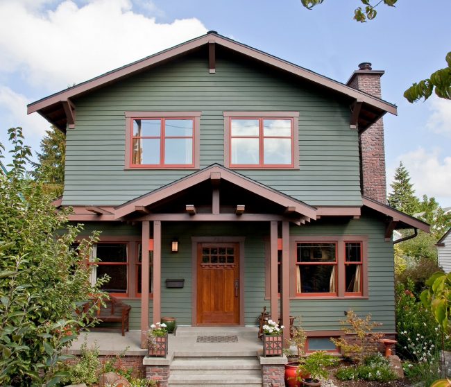 Красивое сочетание зеленого и коричневого цветов в оформлении фасада двухэтажного дома