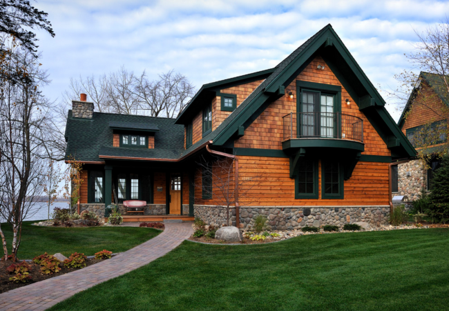 Контраст коричневого бруса и черной крыши в оформлении частного дома