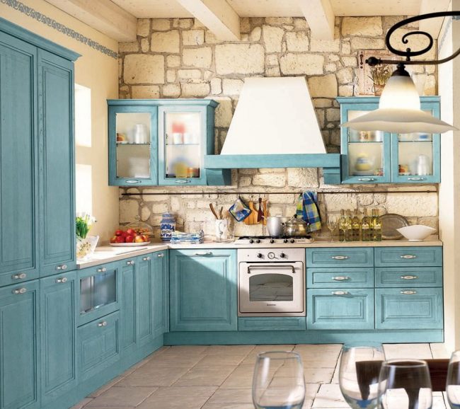 Деревенская кухня в стиле «прованс»: отделка стен из светлого камня, голубой кухонный гарнитур из натурального дерева