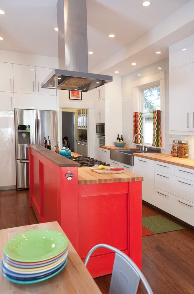 Яркие шторы с геометрическим принтом – акцент на современной кухне, удачно сочетающийся с фасадом кухонного острова насыщенного цвета и разноцветной посудой