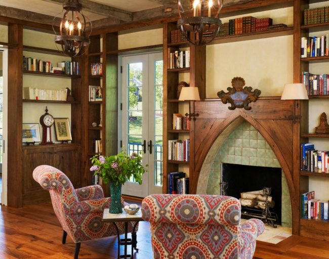 Небольшая комната в загородном доме с элементами готики: деревянная мебель, узорчатая обшивка мебели, стрелкообразный декор камина и светильники "под старину"
