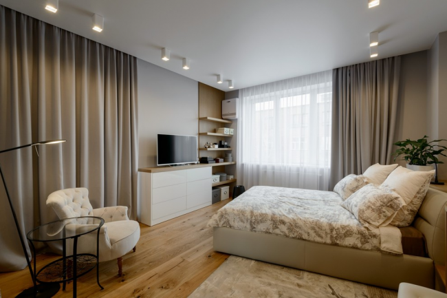 Просторная современная спальня с белым комодом напротив кровати
