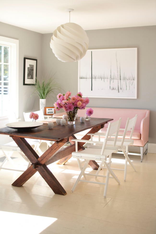 Интересное сочетание складных белоснежных стульев и нежно-розовой софы в дизайне столовой