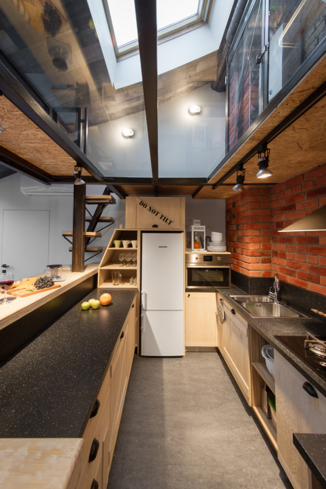 Вытянутая стильная кухня с кирпичной стенкой и окном в потолке
