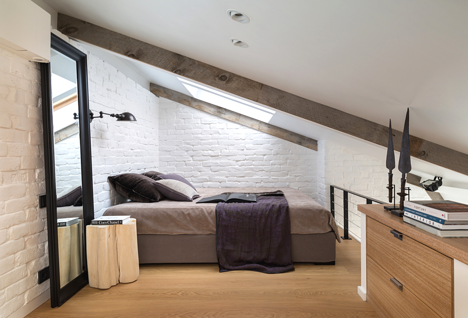 Светлая мансардная спальня с прикроватным светильником, закрепленным на стене над кроватью